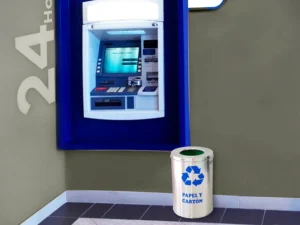 Tacho circular de acero inoxidable 40×23 cm colocado junto a un cajero automático en interior de centro comercial.